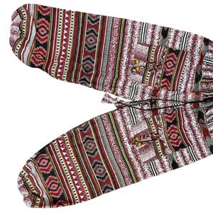 K&ouml;nnte beinhalten: Gemusterte Hose mit Kordelzugbund. Das Design umfasst sich wiederholende rote, schwarze, wei&szlig;e und graue geometrische Formen und Streifen. Der Stoff wirkt leicht und eignet sich f&uuml;r Freizeitkleidung. Die Hose ist wahrscheinlich aus atmungsaktivem Material.