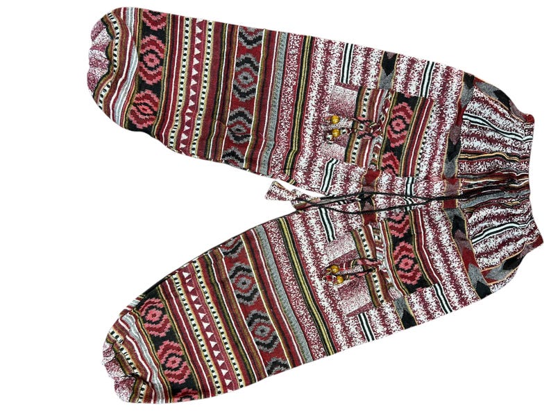 K&ouml;nnte beinhalten: Gemusterte Hose mit Kordelzugbund. Das Design umfasst sich wiederholende rote, schwarze, wei&szlig;e und graue geometrische Formen und Streifen. Der Stoff wirkt leicht und eignet sich f&uuml;r Freizeitkleidung. Die Hose ist wahrscheinlich aus atmungsaktivem Material.