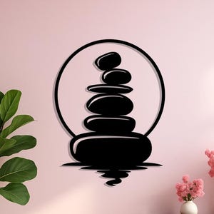 May include: Black metal wall art depicting a stack of smooth stones within a circle, symbolizing balance and serenity. The artwork is mounted on a light pink wall, creating a minimalist and zen-like aesthetic. The design includes a reflection effect.