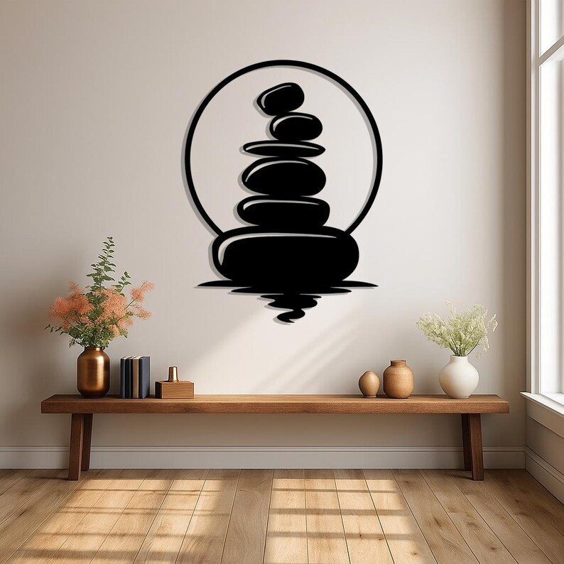 Pu&ograve; includere: Arte murale in metallo nero raffigurante una pila di pietre zen all'interno di un cerchio. L'opera &egrave; montata su una parete di colore neutro sopra una panca in legno. Il design evoca un senso di equilibrio e tranquillit&agrave;.