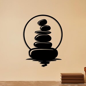 Pu&ograve; includere: Un'opera d'arte da parete in bianco e nero raffigurante una pila di pietre lisce all'interno di un cerchio, con un riflesso sottostante. Il design evoca un senso di equilibrio e tranquillit&agrave;, adatto all'arredamento della casa o a un ambiente spa.