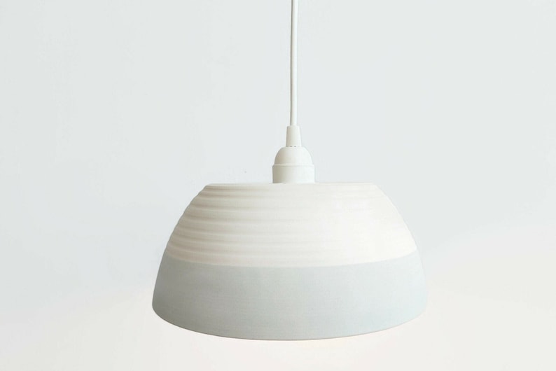 May include: White ceramic pendant light with a light blue glaze on the bottom half of the shade.