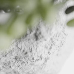 May include: Close-up of a white textured surface with a blurred green plant in the background.
