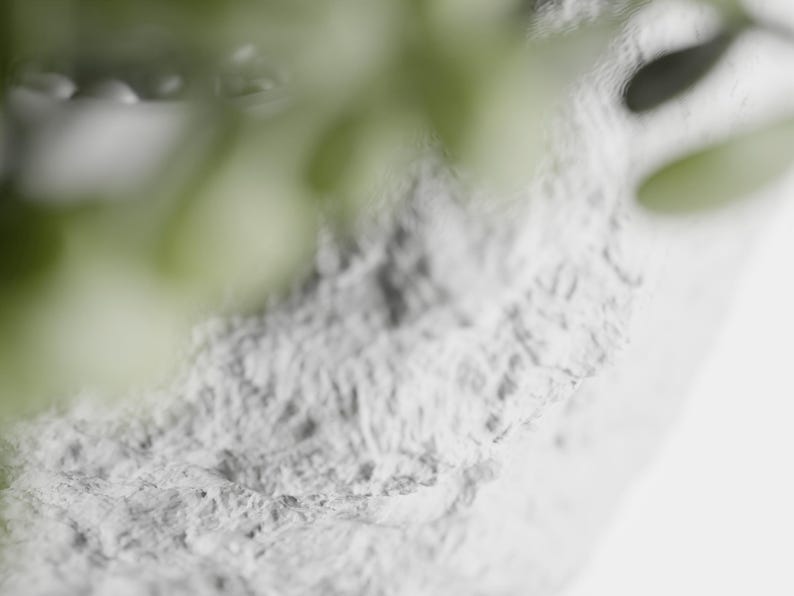 May include: Close-up of a white textured surface with a blurred green plant in the background.