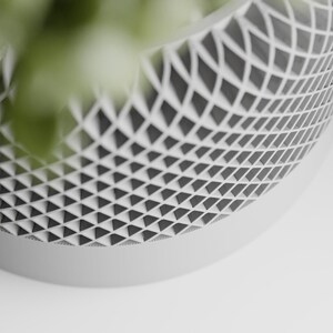 May include: A white ceramic planter with a geometric pattern of triangles. The planter is made of a smooth, matte finish.