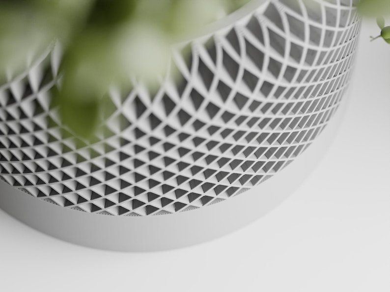 May include: A white ceramic planter with a geometric pattern of triangles. The planter is made of a smooth, matte finish.