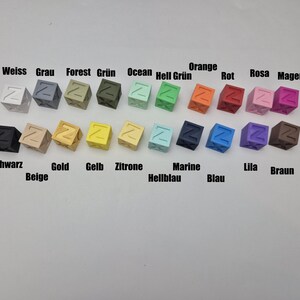 May include: A collection of small, cube-shaped objects in various colors, each with a letter "Z" on one side. Colors include white, gray, forest green, ocean blue, orange, red, pink, and magenta, with text labels in German.