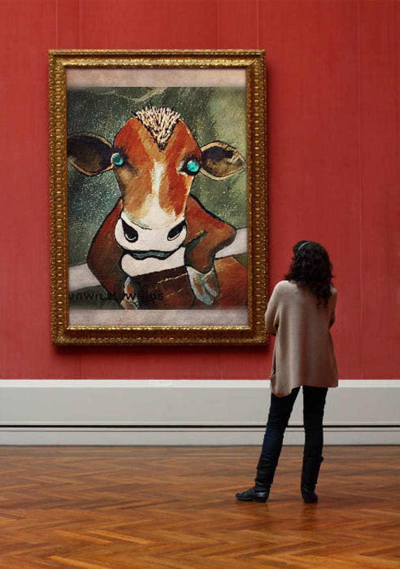 May include: A framed painting of a brown and white cow with blue eyes. The cow is looking directly at the viewer. The painting is in a gold frame and is hanging on a red wall.