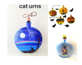 Puede incluir: Urnas redondas de cristal para gatos con escenas pintadas a mano de gatos en paisajes, incluyendo un cielo nocturno con luna y arcoíris, y un gato sentado sobre una pila de libros. Las botellas tienen tapones de corcho, uno con un adorno de cobre.