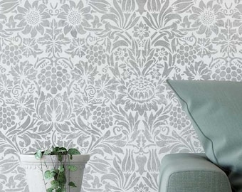 May include: A white wall with a silver floral pattern stencil design. A green sofa with a green pillow is in the foreground.
