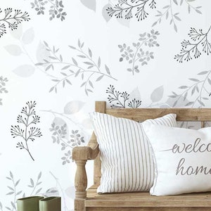 May include: A wooden bench with two cushions, one with a grey and white striped pattern and the other with the text "welcome home" in cursive. The bench is in front of a white wall with a grey floral pattern.