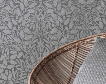 May include: Gray wallpaper with a repeating floral pattern featuring leaves and flowers. A woven wicker chair and a gray textured pillow are in the foreground. The wallpaper has a vintage, botanical design.