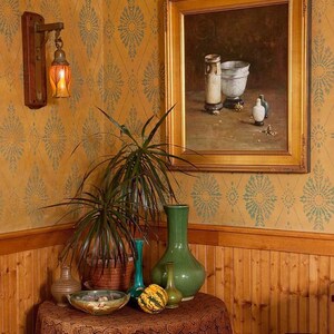 May include: A small table with a brown tablecloth and a green vase with a gourd on top. There are other vases and a bowl on the table. The table is in a room with wood paneling and a patterned wallpaper.