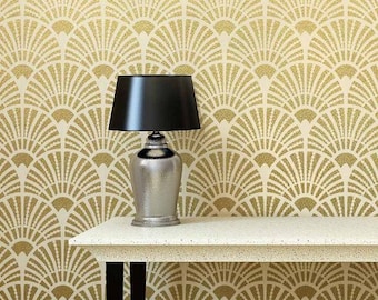 May include: A black lamp with a white shade sits on a white table with a textured surface. The table has black legs. The background is a wall with a gold and white geometric pattern.
