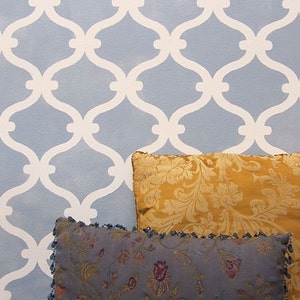 May include: Two decorative throw pillows with floral patterns. The top pillow is a mustard yellow with a gold floral pattern. The bottom pillow is a dark blue with a multi-colored floral pattern. The pillows are in front of a wall with a white trellis pattern.