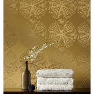 May include: A gold background with a repeating pattern of concentric circles. A stack of white towels and a brown glass bottle with a flower stem are in the foreground.