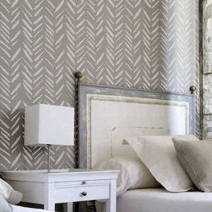 May include: A white bed with a gray headboard and a white nightstand with a drawer. The headboard has a distressed white paint finish. The wall behind the bed is covered in a gray and white chevron patterned wallpaper.