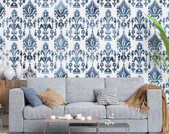 May include: A grey sofa with cushions and a throw blanket in front of a wall with a blue and white patterned wallpaper.