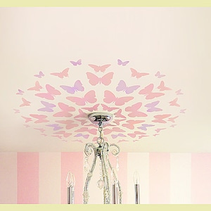 May include: A ceiling decorated with a pattern of pink and purple butterflies, centered around a silver chandelier.