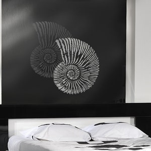 May include: Two gray ammonite shell stencils on a black background. The stencils are layered on top of each other, with the larger shell in the back and the smaller shell in the front. The shells are detailed with intricate lines and curves.