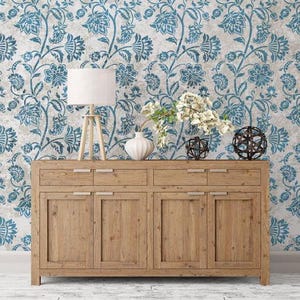 May include: A wooden dresser with four drawers and four doors. The dresser is in front of a wall with a blue and white floral pattern.