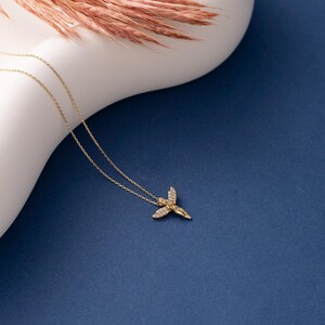 May include: A gold chain necklace with a small angel pendant. The angel is detailed with small diamonds and has its wings spread out.