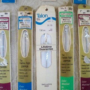 May include: Four packages of different sizes of white metal zippers. The packages are labeled with the brand name "J. & P. Coats" and "Talon". The zippers are for dresses, skirts, and separating garments. The packages also include the price and size of the zippers.
