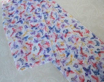 May include: A white sheer scarf with a colorful butterfly print. The butterflies are in shades of pink, purple, blue, and yellow.