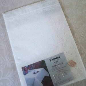 May include: White eyelet tablecloth with a label that reads "Eyelet by PS Perma-Lace" and lists care instructions and sizes. The label also shows a white tablecloth with a floral centerpiece on a table.
