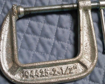 May include: A silver C-clamp with a threaded screw and a handle. The clamp has a 1 1/2 inch opening and the text "1 1/2" is printed on the clamp.