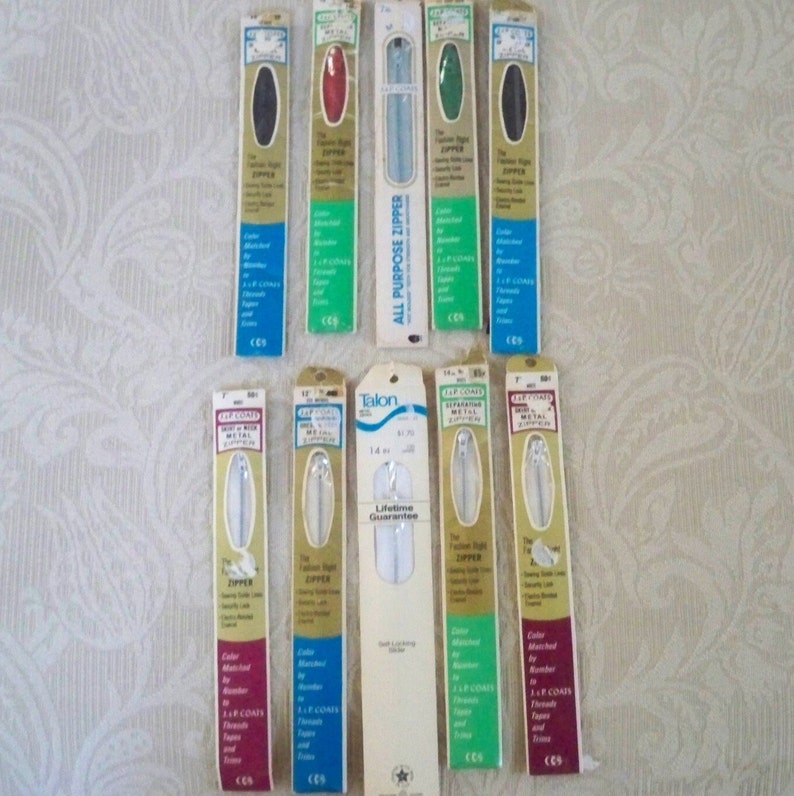 May include: A collection of 12 white, black, red, green, and silver zippers in individual packaging. The packaging features the brand name "Talon" and the text "Lifetime Guarantee".