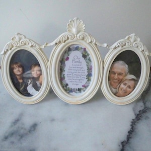 May include: A triple oval photo frame in cream color. The frame holds three photos, with a decorative floral design at the top. The center frame has the text "Our Family" with a poem. The other two frames hold photos of people.