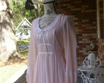 May include: A pale pink vintage nightgown with lace trim and a satin ribbon tie at the neckline. The gown has long sleeves and a flowing skirt.