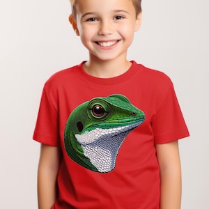Op de afbeelding: Een jonge jongen draagt een rood T-shirt met een groene hagedis afbeelding op de voorkant. De hagedis heeft een witte onderkant en een zwart oog.
