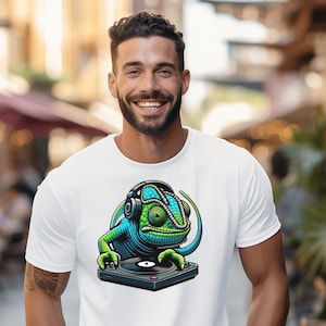 Puede incluir: Camiseta blanca con un gráfico de un camaleón verde con auriculares y sosteniendo un tocadiscos.