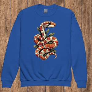 May include: A royal blue sweatshirt with a colorful illustration of a snake curled up with leaves. The snake is orange, red, and white.