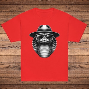 May include: A red t-shirt with a graphic of a cobra wearing sunglasses and a fedora hat.