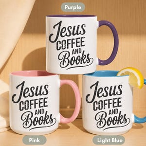 May include: Three white ceramic mugs with the text "Jesus Coffee and Books" in black script. Each mug has a different colored handle and interior: purple, pink, and light blue. A lemon slice rests on the rim of the light blue mug.