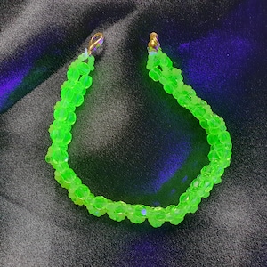 Könnte beinhalten: Eine grüne Glaskette mit goldenen Verschlüssen. Die Kette besteht aus kleinen, runden Perlen und ist auf einer doppelten Schnur aufgefädelt.