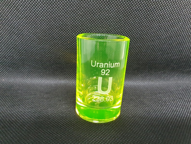 May include: A neon green shot glass with the text "Uranium 92 U 238.03" printed on the side.