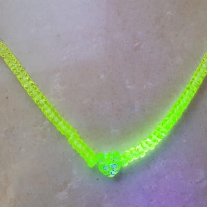 Könnte beinhalten: Eine gelbe Glaskette mit einem herzförmigen Anhänger. Die Kette besteht aus kleinen, runden Perlen und hat einen goldenen Verschluss.