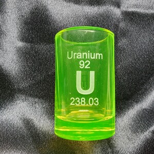 May include: A green shot glass with the text "Uranium 92 U 238.03" printed on it.