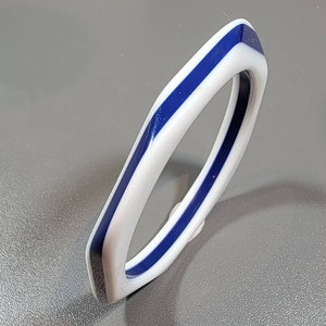 May include: A white bangle bracelet with a blue stripe around the edge.