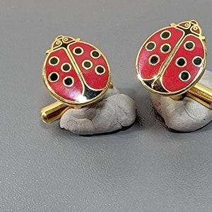 May include: A pair of gold-tone cufflinks featuring red and black enamel ladybug designs.