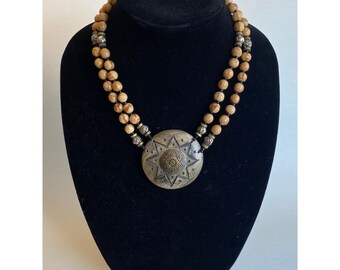 Collana boho a doppio filo con perline di corallo tigrato e medaglione intagliato a forma di raggio di sole.