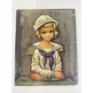 May include: Vintage painting of a young person in a sailor outfit. The person has blonde hair, large eyes, and is wearing a white sailor hat with an anchor emblem. The sailor suit is white with a blue necktie. The painting is signed "EDEN-".