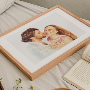 May include: A framed watercolor portrait of a couple, with the man kissing the woman's cheek. The artwork is in a light wood frame with a white mat. The woman has long, flowing auburn hair and is smiling. The man has dark hair and a beard.