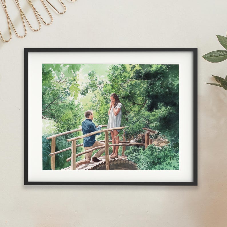 May include: Watercolour painting depicting a marriage proposal. A man kneels on a wooden bridge, offering a ring to a woman. The scene is set amidst verdant foliage, creating a romantic outdoor setting. The artwork is framed in a black border.