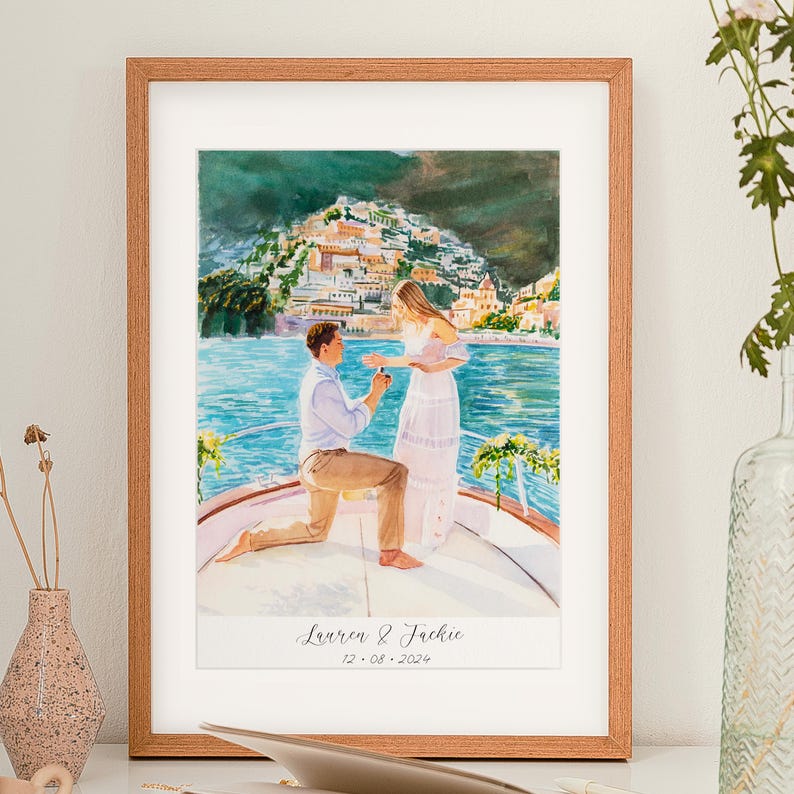 May include: Watercolor painting in a wooden frame depicts a marriage proposal on a boat with a coastal town backdrop. The couple is in the foreground, with the text "Lauren & Jackie 12.08.2024" at the bottom.