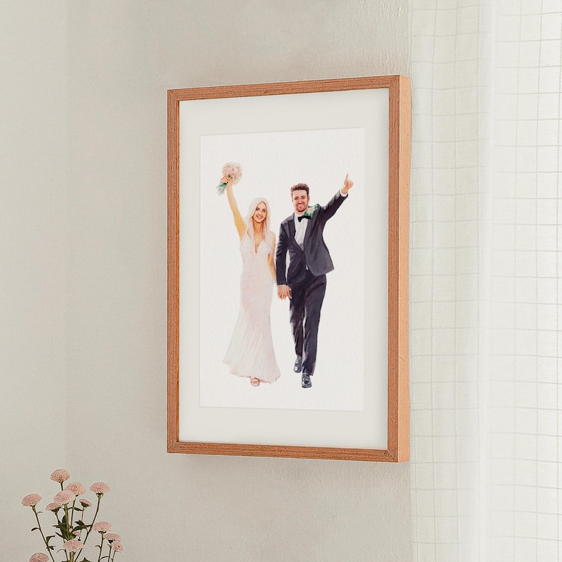 May include: A framed watercolor print of a wedding couple. The bride wears a white dress and holds a bouquet. The groom wears a black suit and raises his arm. The frame is made of light brown wood.